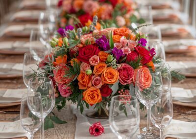 Bunte Hochzeitsdekoration mit einer großen Blumenarrangement aus Rosen und anderen Blumen auf einem langen Tisch.