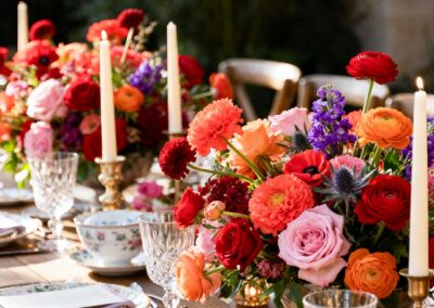 Bunte Hochzeitsdekoration mit Blumenarrangements und Kerzen auf einem Tisch.